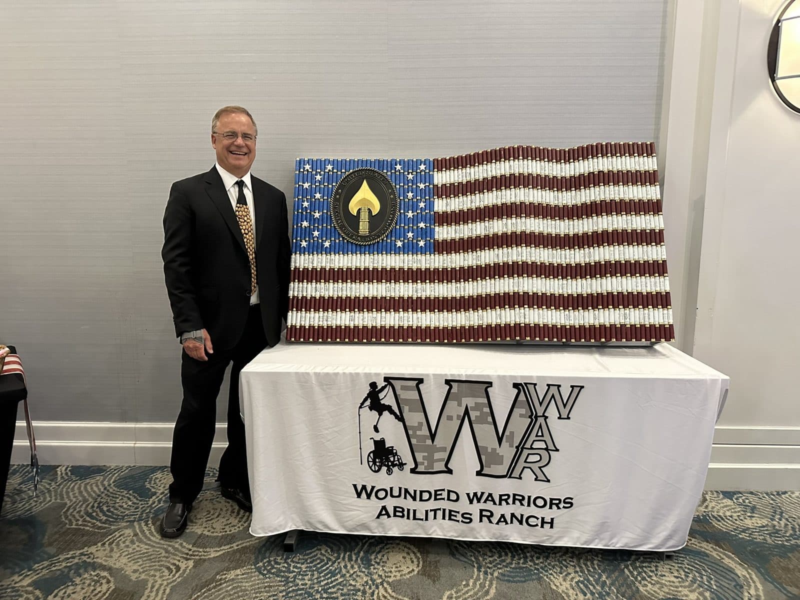 Michael Bell with his shotgun shell flag bearing the Special Operations emblem at a Wounded Warriors Abilities Ranch event