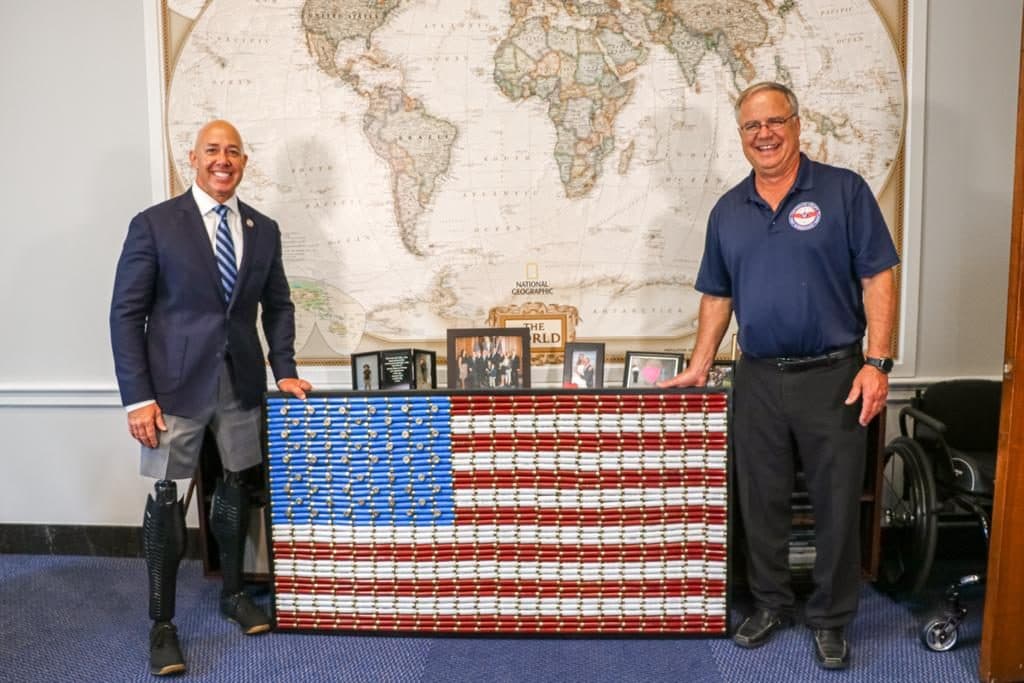 Michael Bell and Congressman Brian Mast with a shotgun shell flag